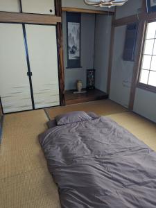 a large bed in a room with large windows at 小江戸川越ハウス in Kawagoe