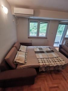 a bed in a room with a couch and two windows at Zagrebska flat in Skopje