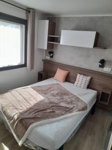 a bedroom with a large bed with a blanket on it at camping la carabasse in Vias