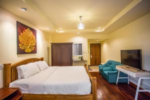 a bedroom with a bed and a couch and a television at Prince Hotel Chiang Mai in Chiang Mai