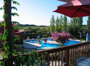 - un balcon avec une piscine entourée d'un parasol dans l'établissement Le Cottage - Gîtes De La Tournerie, à Gémozac