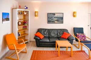 ein Wohnzimmer mit einem schwarzen Ledersofa und 2 Stühlen in der Unterkunft Ferienappartement Fraenzi mit herrlichem Seeblick in Sassnitz