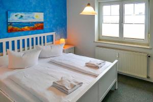 ein Schlafzimmer mit einem weißen Bett mit zwei Handtüchern darauf in der Unterkunft Ferienappartement Fraenzi mit herrlichem Seeblick in Sassnitz