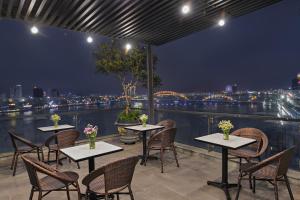 a patio with tables and chairs and a view of the city at Avora Hotel in Da Nang