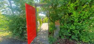 una puerta roja abierta que conduce a una pasarela en GLÜCK HOMES Baumhaus en Ippesheim