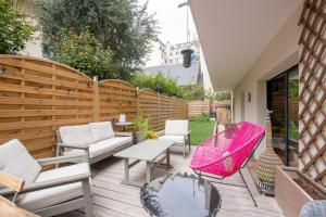 um pátio com mobiliário branco e uma cadeira rosa em Veeve - Tranquility Terrace em Boulogne-Billancourt