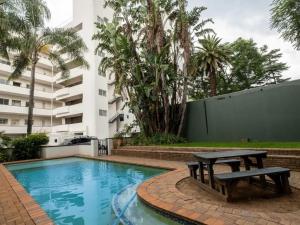 a swimming pool with a picnic table next to a building at Lovely 3 Bedroom Unit Sandton in Johannesburg