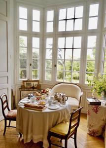 Un comedor con mesa y sillas y ventanas. en Villa du Châtelet, en Choisy-au-Bac