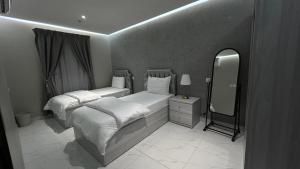 Zimmer mit 2 Betten und einem Spiegel in der Unterkunft لاقونا للشقق المخدومة in Al-Hasa
