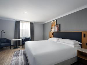 Habitación de hotel con cama blanca grande y escritorio. en Edinburgh Marriott Hotel Holyrood en Edimburgo