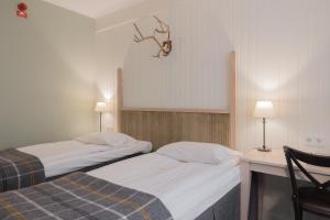 2 camas en una habitación con escritorio y silla en Hotel Bishops Arms Piteå, en Piteå