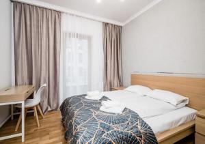 Un dormitorio con una cama y un escritorio y una ventana. en GH Luxury Apartment, en Cracovia