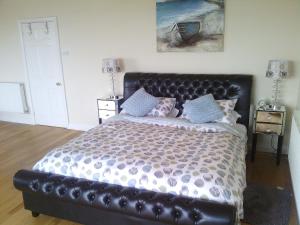 a bedroom with a large bed with a black leather headboard at Yew Tree House in Paignton