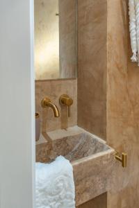 Manus Dei Exclusive Suites في بيثاغوريو: حمام مع حوض وحوض استحمام مع مرآة