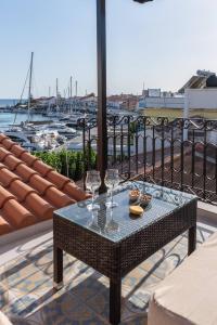 a table with two glasses on a balcony with a marina at Manus Dei Exclusive Suites in Pythagoreio