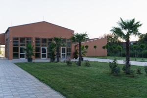 a building with palm trees in front of a yard at Luby Panzió 