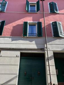 a pink building with a green door and windows at Residence Le due Corti in Imola