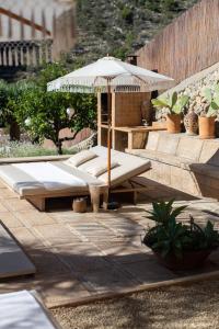 a patio with two beds and an umbrella at Villa Can Rasca in Caimari