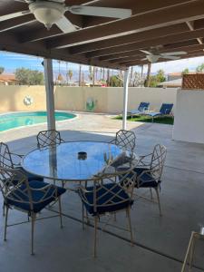une table et des chaises en verre sur une terrasse avec piscine dans l'établissement Desert oasis, à La Quinta