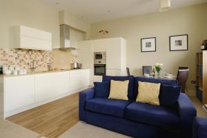 Il comprend un salon avec un canapé bleu et une cuisine. dans l'établissement Beachcomber - Aldeburgh Coastal Cottages, à Aldeburgh