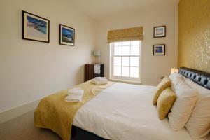 - une chambre avec un grand lit blanc et une fenêtre dans l'établissement Beachcomber - Aldeburgh Coastal Cottages, à Aldeburgh