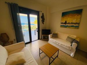 una sala de estar con 2 sofás blancos y una mesa. en Sea view Apartment 5 with roof top terrace, Almyrida en Almirida