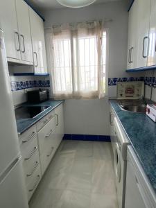 una cocina con armarios blancos y fregadero en Apartamento Costa de Sancti Petri by Chiclana Dreams en Novo Sancti Petri