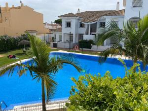 una piscina frente a una casa con palmeras en Apartamento Costa de Sancti Petri by Chiclana Dreams en Novo Sancti Petri