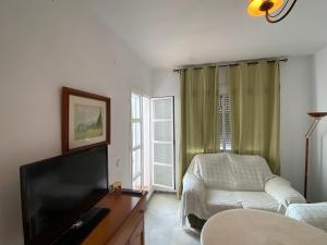 a living room with a flat screen tv and a couch at Apartamento Costa de Sancti Petri by Chiclana Dreams in Novo Sancti Petri
