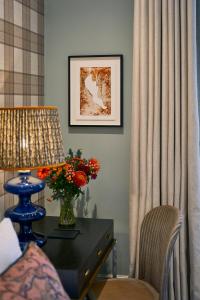 a room with a table with a lamp and a vase of flowers at The Tophams Hotel in London