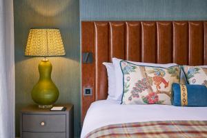 a bedroom with a bed with a lamp on a night stand at The Tophams Hotel in London