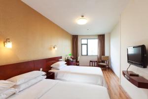 a hotel room with two beds and a flat screen tv at Milo Hotel - Near Shanghai Hongqiao National Exhibition Center in Shanghai