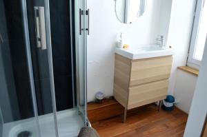 La salle de bains est pourvue d'une douche et d'un lavabo. dans l'établissement À l'est - Studio vue mer sur la digue, à Arromanches-les-Bains