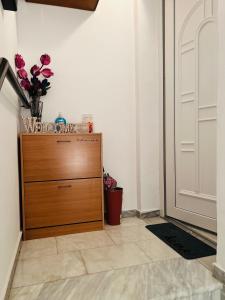 a dresser with a vase of flowers on it next to a door at Cozy place in Kozani