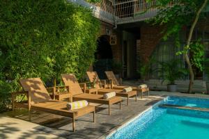 a row of lounge chairs next to a swimming pool at The Artist House Udaipur in Udaipur