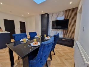 a dining room with a table and blue chairs at 3 Bedroom Stylish Home Merthyr in Merthyr Tydfil