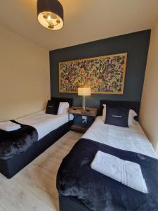 two beds in a room with a painting on the wall at 3 Bedroom Stylish Home Merthyr in Merthyr Tydfil