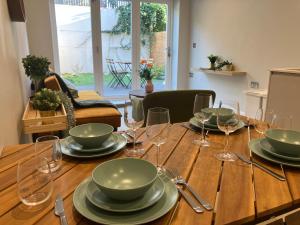 a wooden table with plates and wine glasses on it at Spectacular 2 Bed Apartment With Lovely Terrace - 1 The Southwell in London
