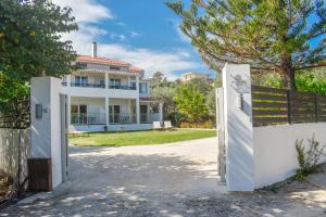 une maison blanche avec un portail et une clôture dans l'établissement Ktima Holiday House, à Skiathos Chora