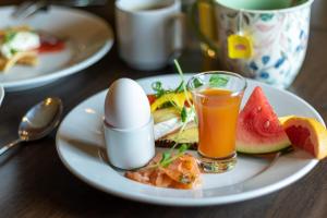 un plato de comida con un huevo y un vaso de zumo de naranja en First Hotel Grand Falun en Falun