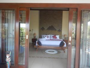 - une chambre avec un lit et une porte en verre dans l'établissement Villa Omah Semar, à Tulamben