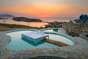 a swimming pool with a table and the ocean at sunset at Agalia Luxury Suites in Tzamaria
