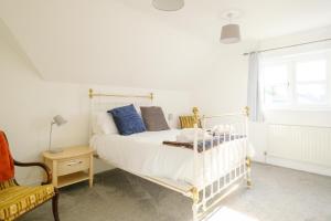 1 dormitorio con 1 cama blanca y 1 silla en 4 The Birches - Aldeburgh Coastal Cottages en Aldeburgh