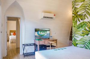 Eden Beach Resort by EHM في كوه رونغ ساملوم: غرفة نوم مع مكتب وسرير مع تلفزيون