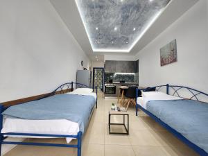 a room with two beds and a kitchen with a table at The Blue Beach Apartments in Nea Peramos