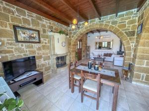 sala de estar con mesa y pared de piedra en Private Pool with Sea & Mountain View ,Full Privacy - Villa Kyriaki, en Kissamos