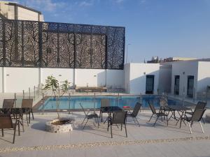 a patio with tables and chairs next to a pool at مورايا Murraya in Abyār ‘Alī