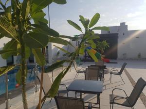 a patio with chairs and tables and a pool at مورايا Murraya in Abyār ‘Alī