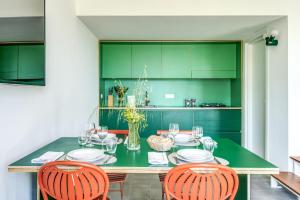 comedor con mesa verde y sillas en I Monolocali, en SantʼAgata sui Due Golfi