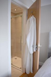a bathroom with a shower and a robe hanging on a door at Grimisdale Guest House in Leverburgh